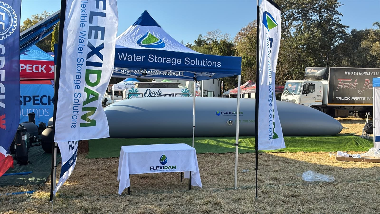 A filled FlexiDam pillow tank behind the branded gazebo on the stand at KragDag 2026