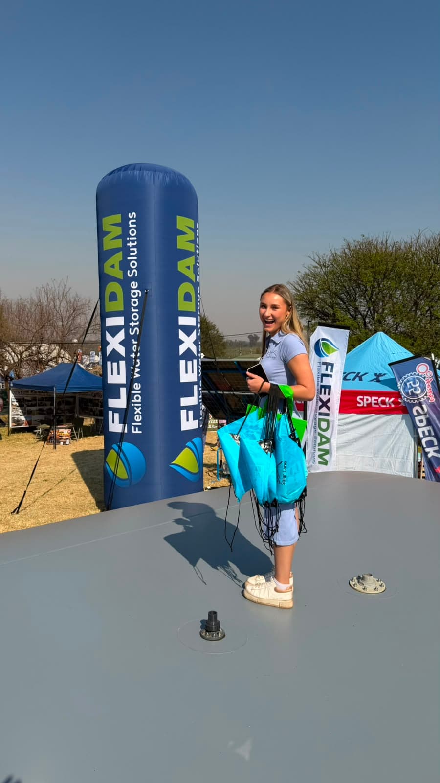 A member of the FlexiDam team carrying branded tote bags on top of a filled pillow tank at KragDag 2026