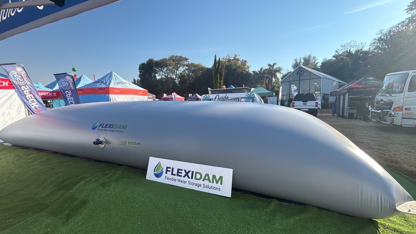 A filled FlexiDam pillow tank on the stand at KragDag 2026, with the FlexiDam logo printed on the grey membrane