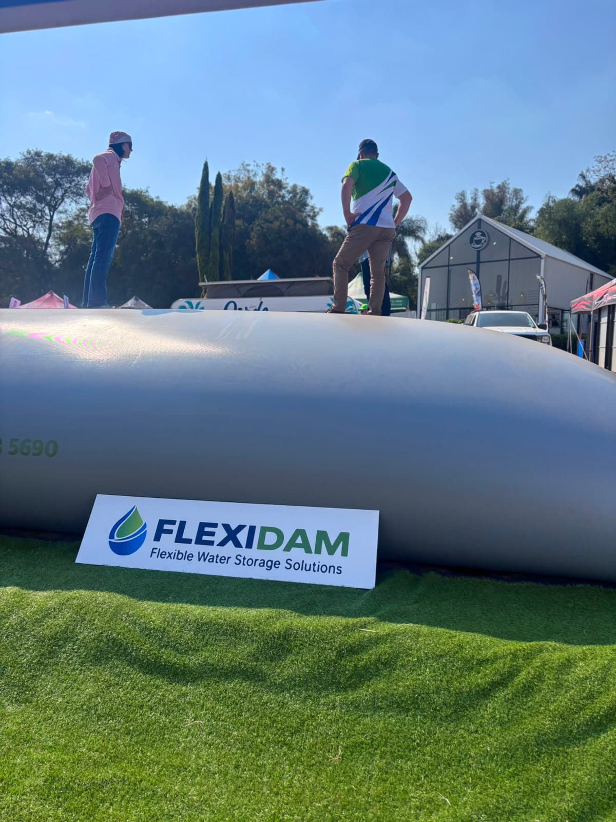 Two visitors standing on top of a filled FlexiDam pillow tank at KragDag 2026